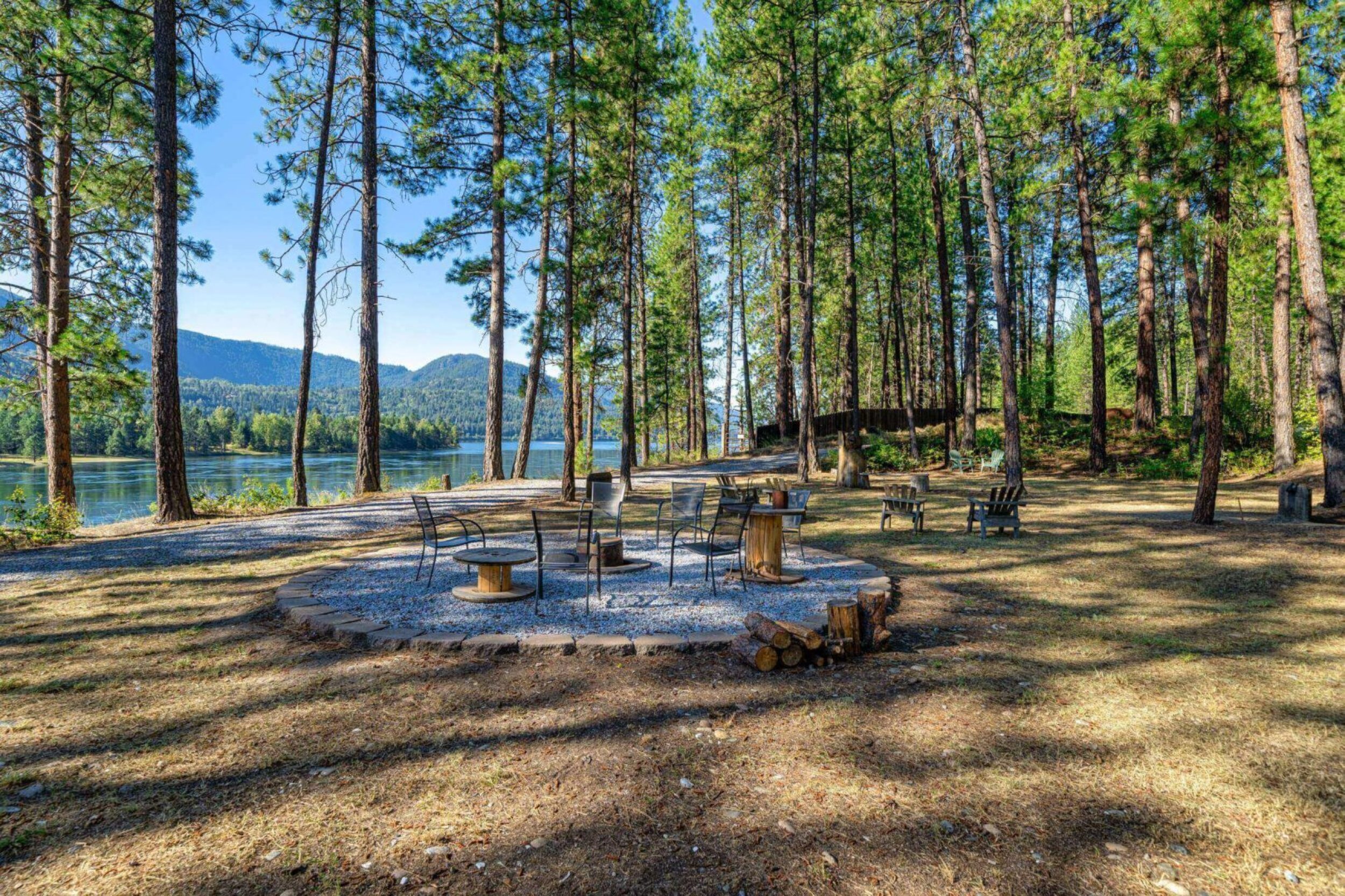 Forest clearing with chairs by a lake.