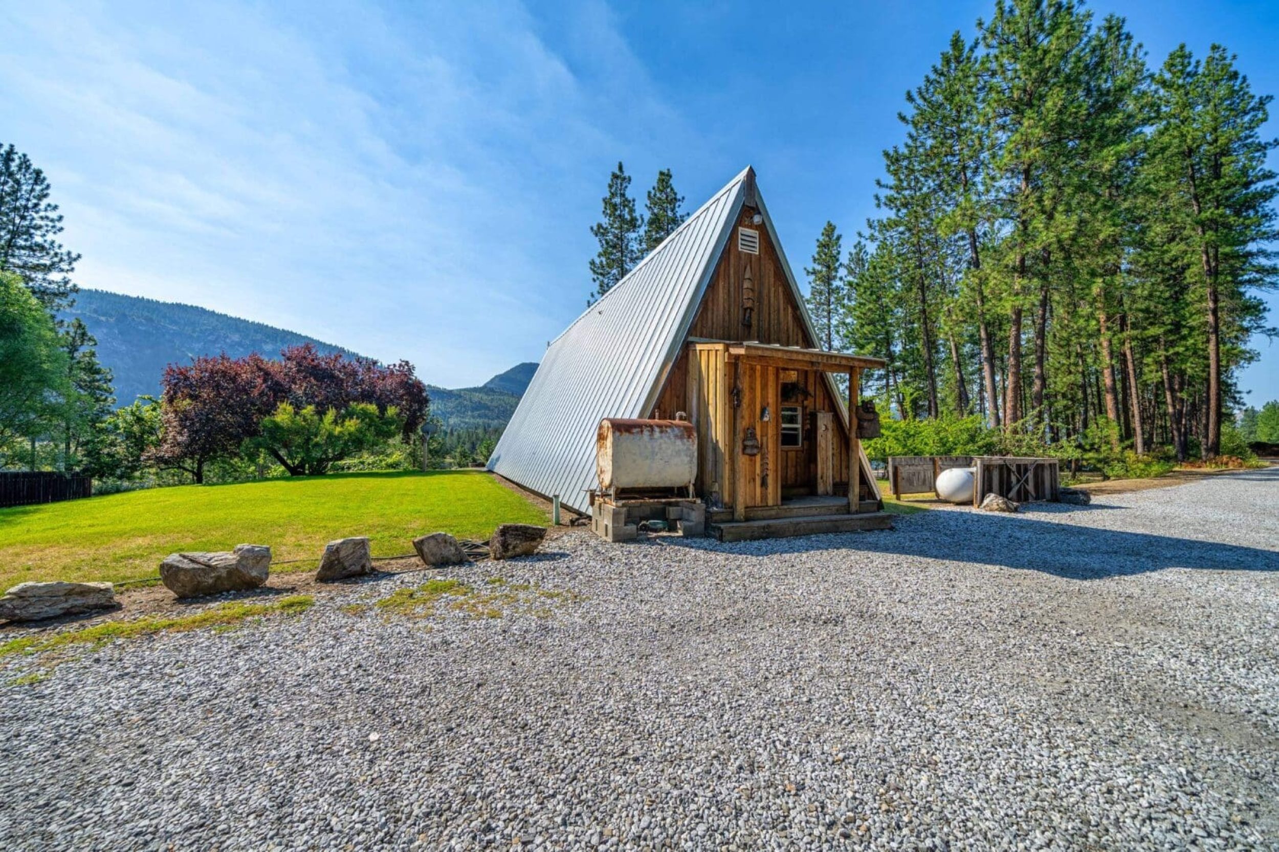 A-frame cabin surrounded by trees and mountains.