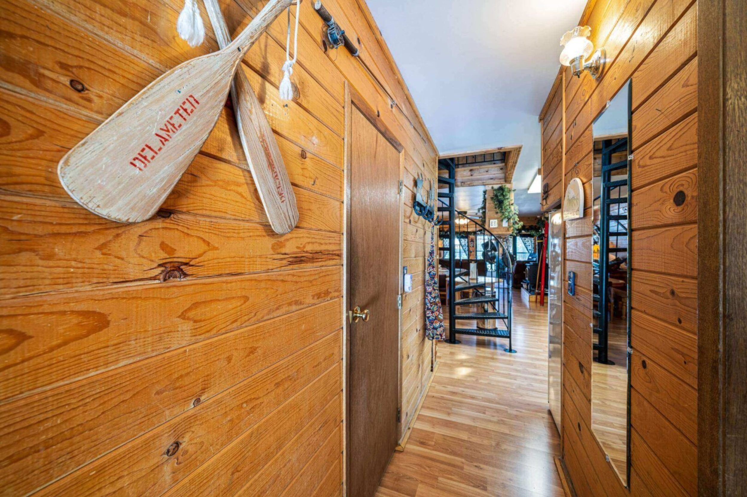 Wooden hallway with spiral staircase and mirrors.