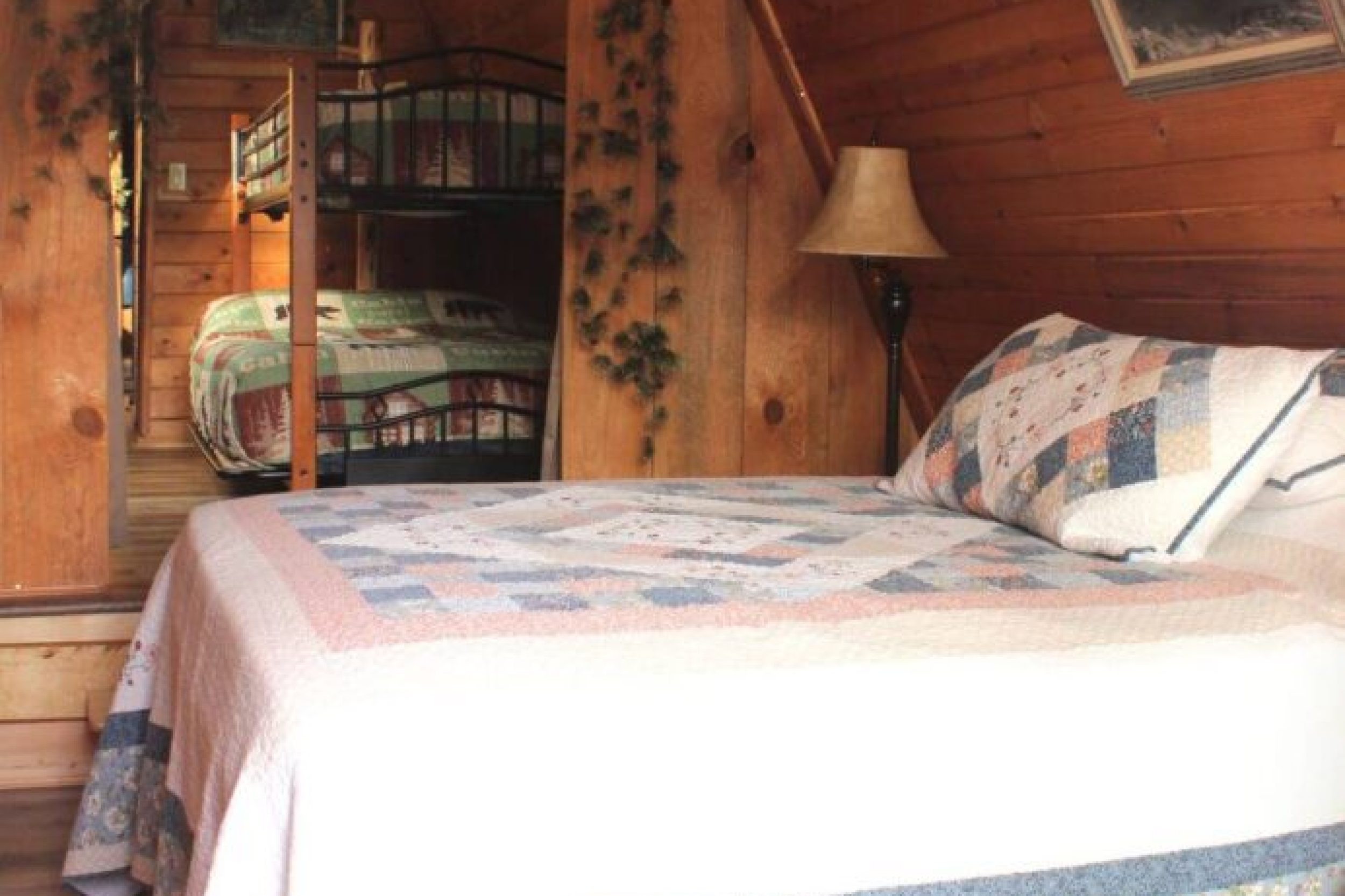 Cozy wooden bedroom with quilted bed.