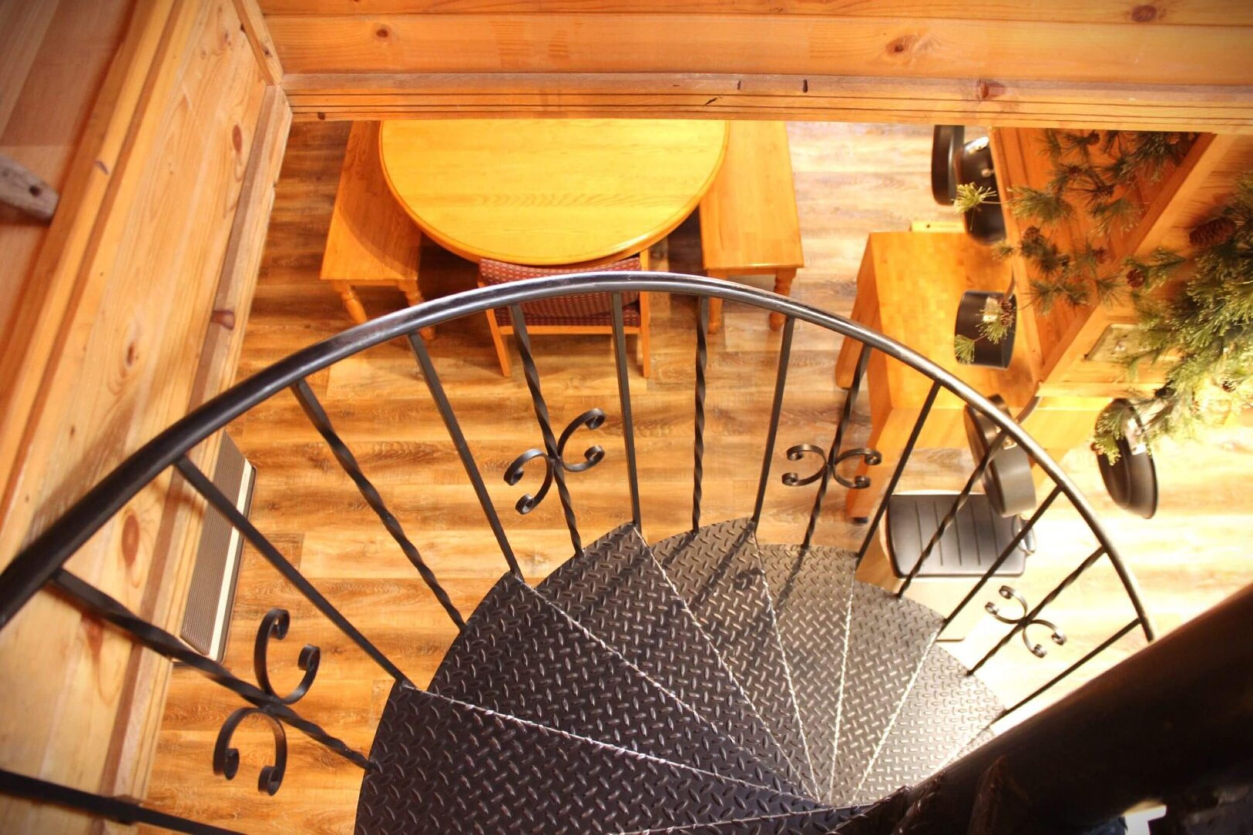 Spiral staircase leading to wooden dining area.